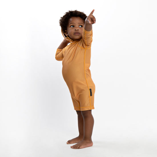 This picture shows a boy wearing the ribbed golden, UPF50+ baby swimsuit