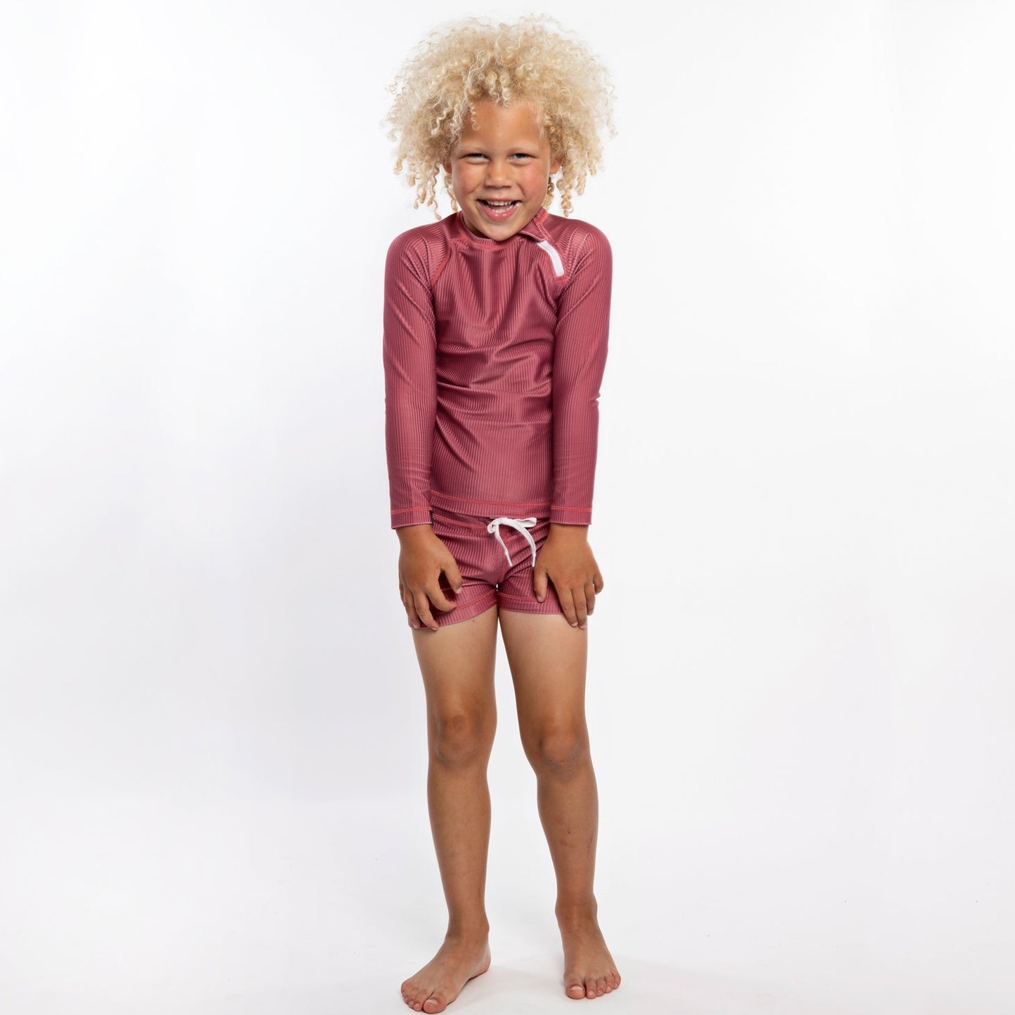 This picture shows a boy wearing the ruby red, UPF50+ swim shorts