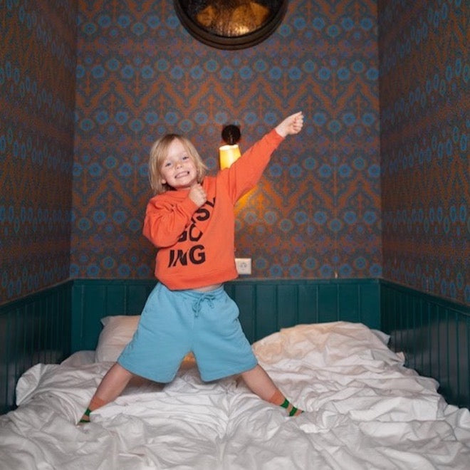 This picture shows a boy wearing the orange easy going crew neck sweater. Made out of organic cotton 