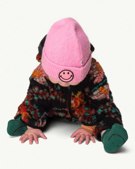 This picture shows a baby wearing the soft knitted pink beanie with a funny smily patch