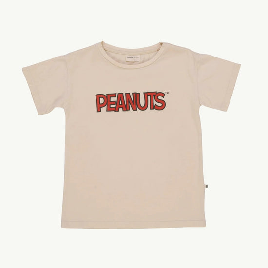 This picture shows an off white kids t-shirt with Peanuts written on the front. 