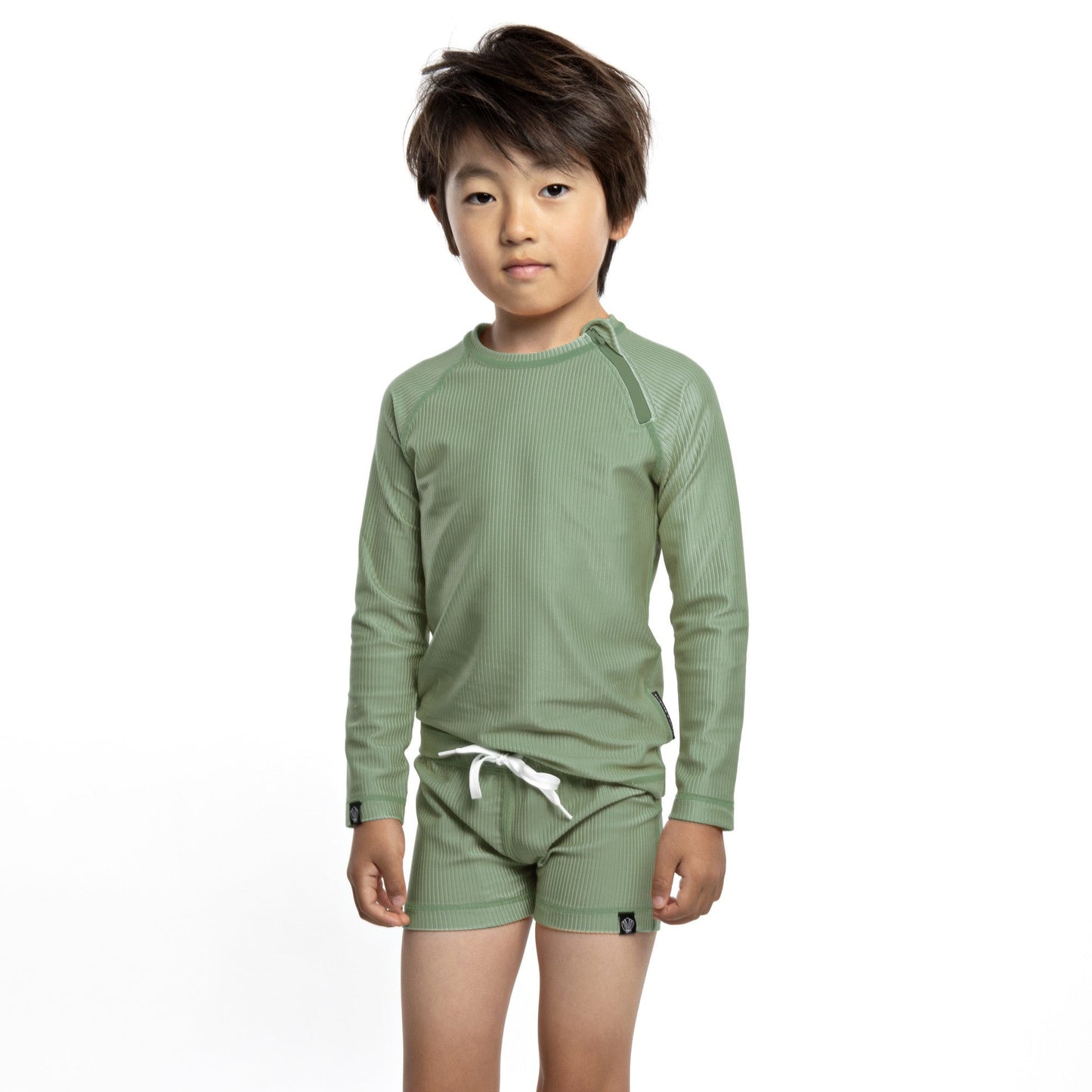 This picture shows a boy in a ribbed basil green, UPF50+ long sleeve rashie