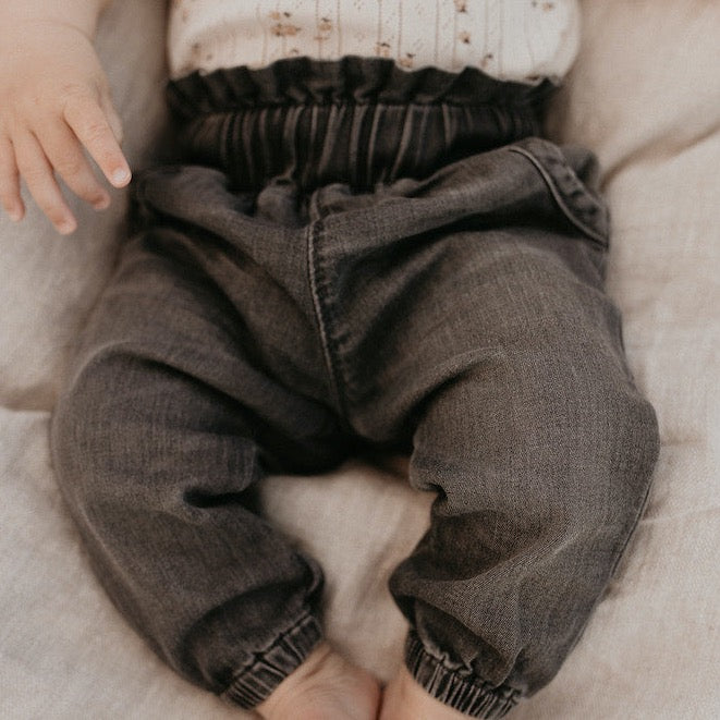 This picture shows a bab wearing washed black baby denim. Made out of gos organic cotton. 