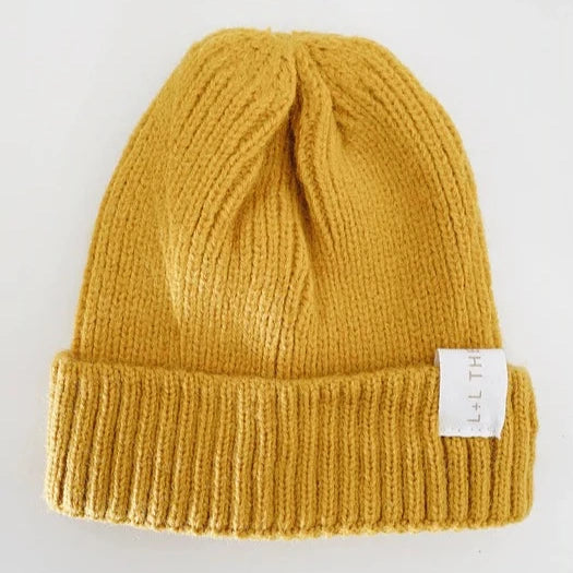 This picture shows a  warm soft knit kids winter hat in a cool mustard yellow colour. from 6 months to 6 years