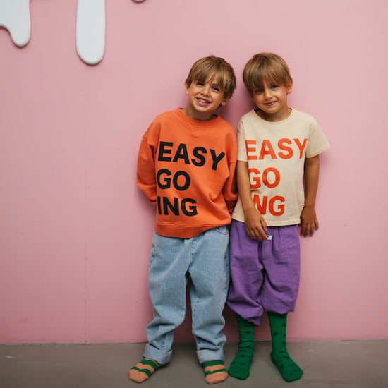 This picture is showing a boy wearing the orange easy going sweater. made out of organic cotton. 