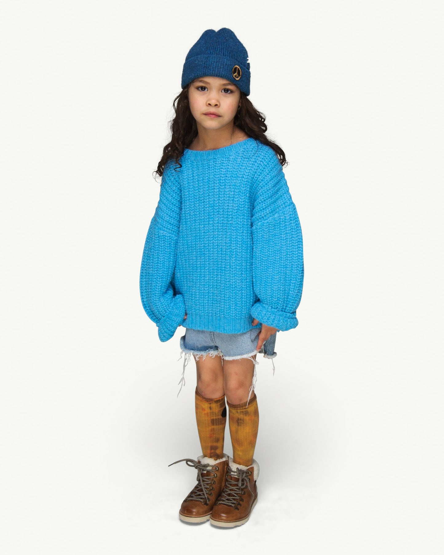 This picture shows a girl wearing a soft knitted blue beanie with a peace patch