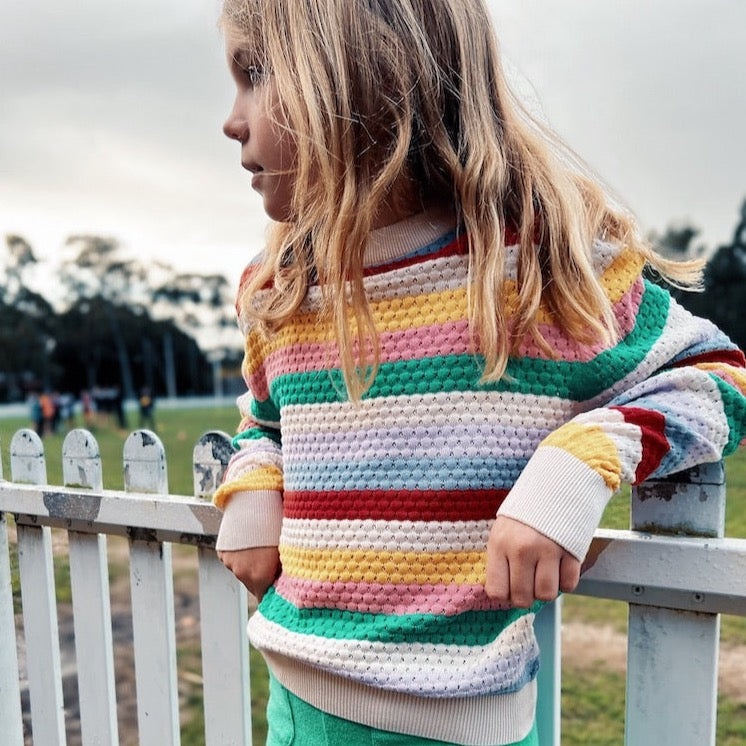 this picture show a girl wearing th knitted rainbow jumper