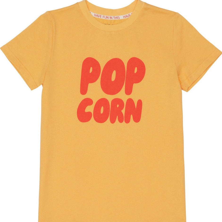 This picture shows a yellow cotton t-shirts for kids. With red letters stating popcorn. 