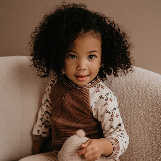 This picture shows a girl wearing the GOTS organic cotton cardigan iin the nut colour.