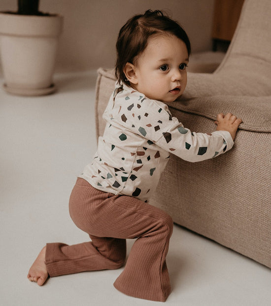 This picture shows a girl wearing the flared pants in the colour rib nuts, made out of 100% gots organic cotton