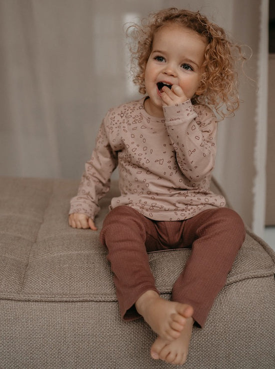 This picture shows a girl wearing the gots organic ribbed cotton leggings in the colour nuts