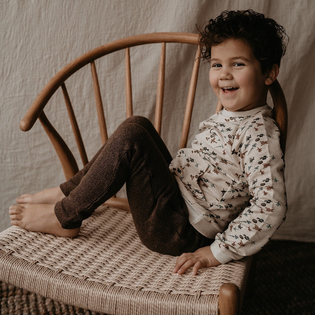 This picture shows a child wearing a off white sweater with 2 front pockets. It has green, red, blue nasca print. It is made out of 100% organic cotton.