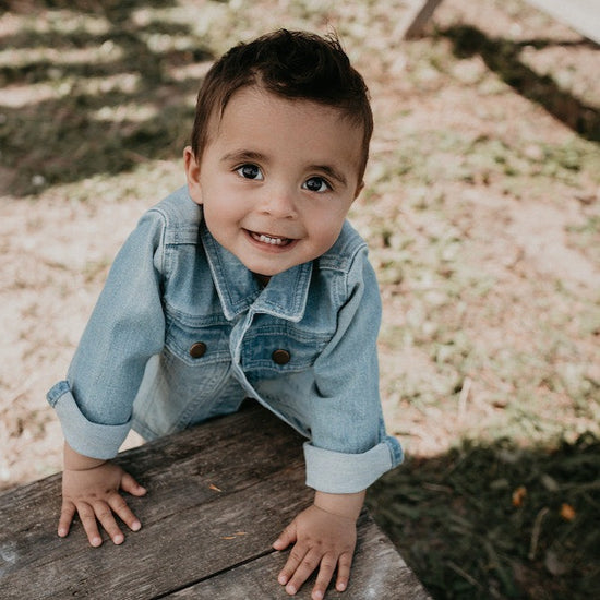 This picture shows a boy wearing blue denim jacket for kids with sturdy buttons at the front. Made from Organic cotton and available up until 6 years.