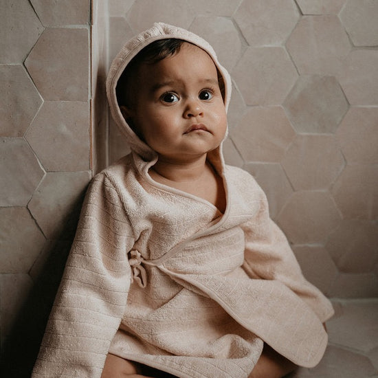 This picture shows a baby bath robe in peach blush. Made from 100% Gots organic cotton in the most comfortable, stretchy and absorbent towel. 