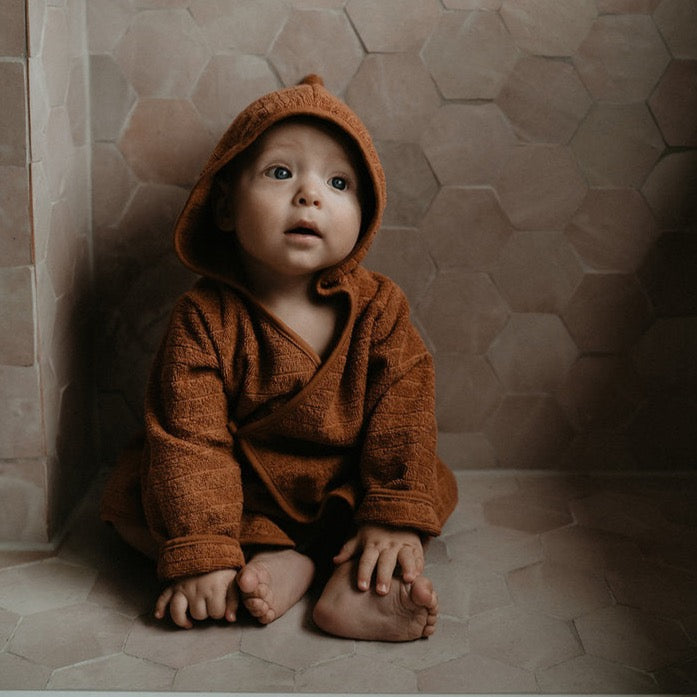 This picture shows a baby bath robe in toffee. Made from 100% Gots organic cotton in the most comfortable, stretchy and absorbent towel.