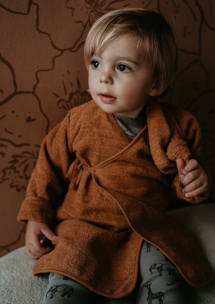 This picture shows a baby bath robe in toffee. Made from 100% Gots organic cotton in the most comfortable, stretchy and absorbent towel. 